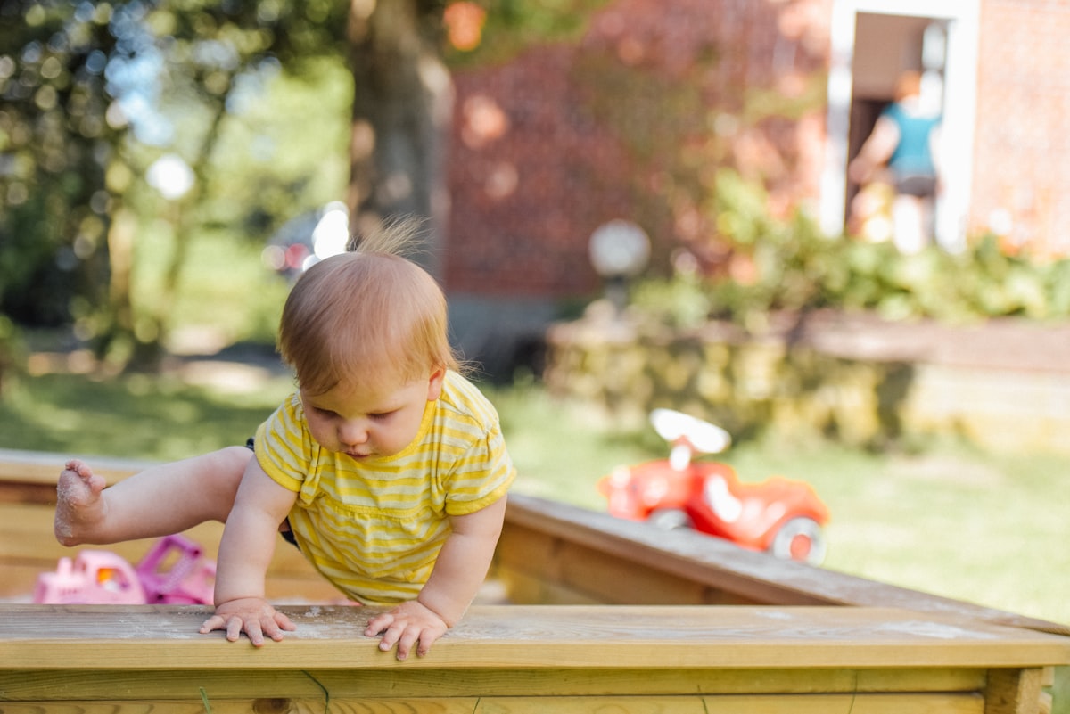 Toddler climbing confidently outdoors, building balance and motor skills