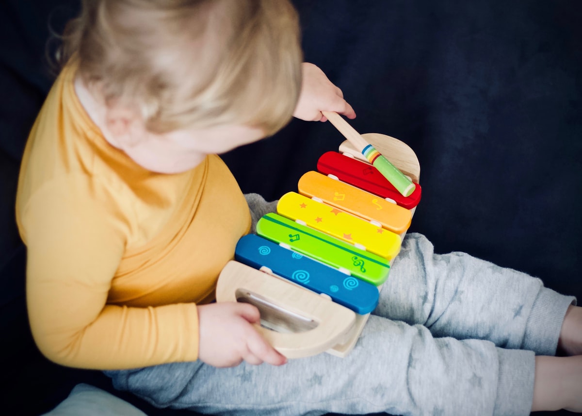 Toddler joyfully playing a wooden xylophone toy