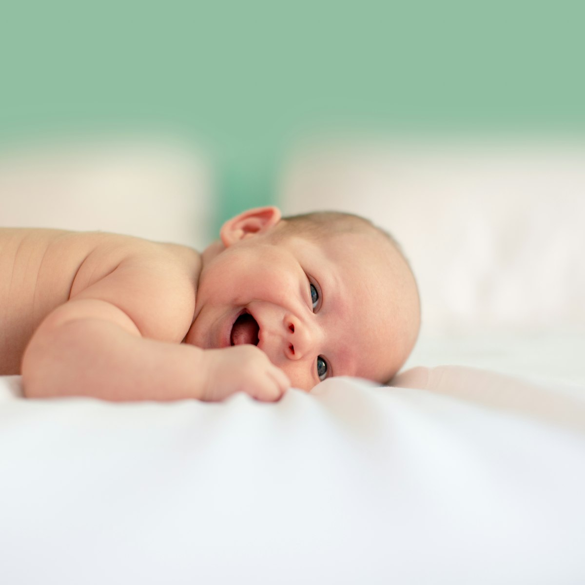 Laughing baby lying on a soft organic cotton blanket
