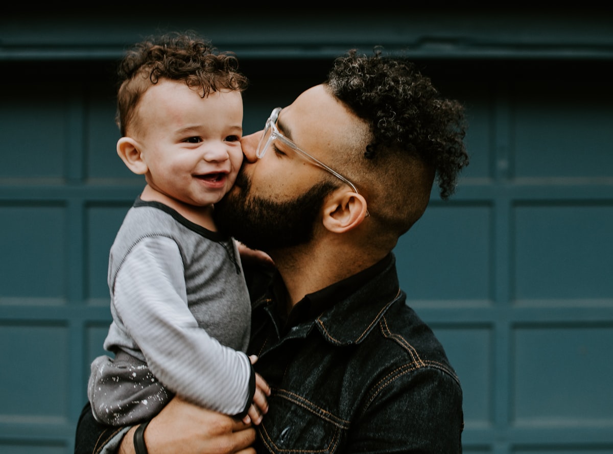 Father tenderly kissing his baby's cheek while holding him