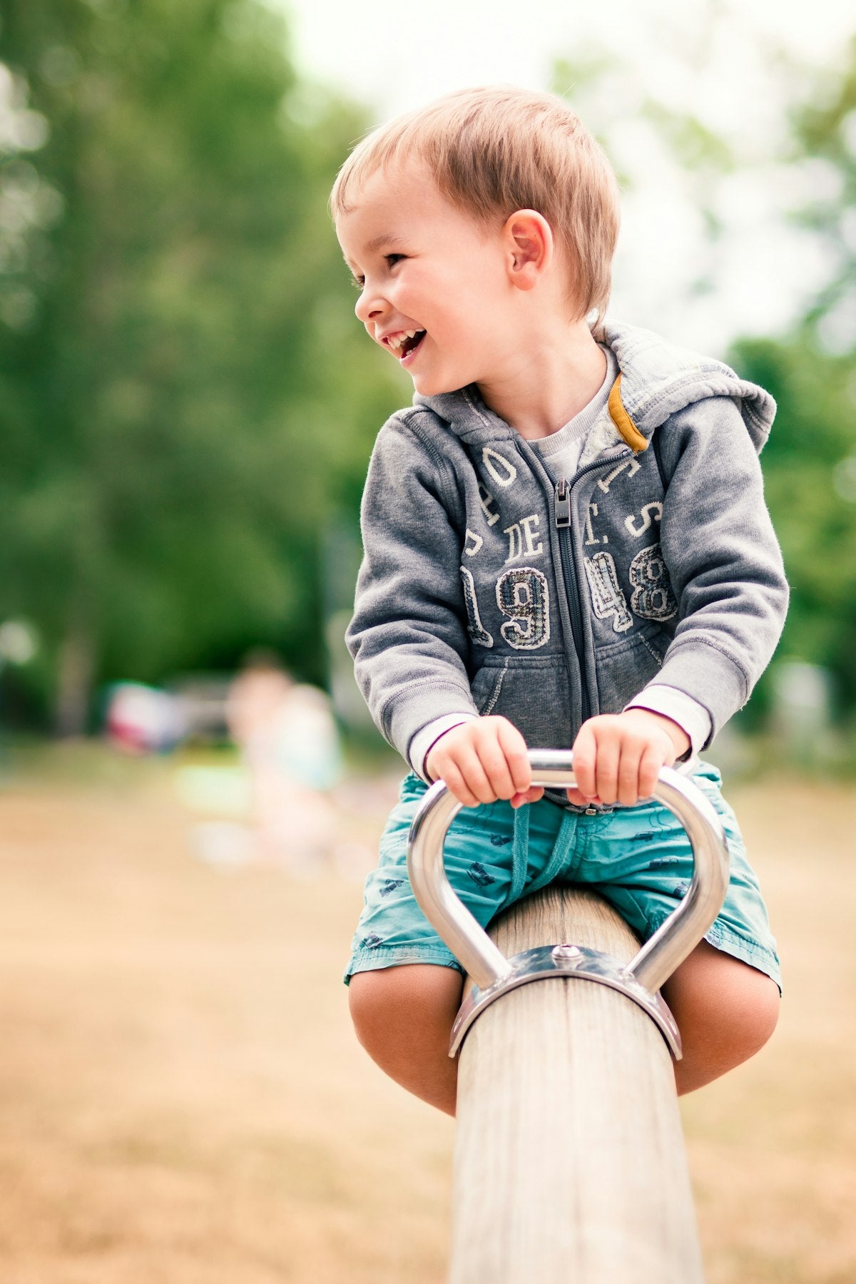 Toddler laughing joyfully on a seesaw outdoors